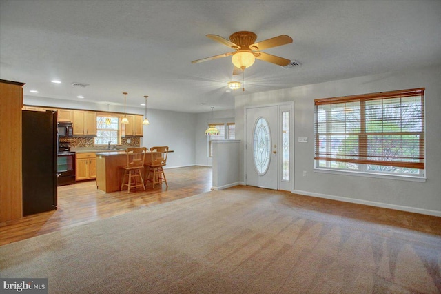 foyer entrance featuring light carpet, sink, and ceiling fan