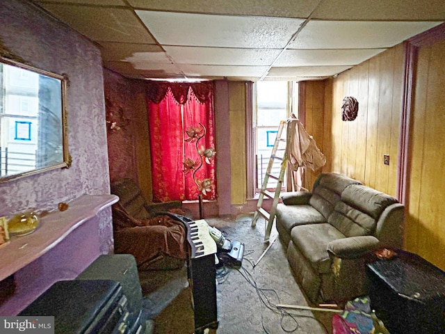 sitting room featuring a paneled ceiling and wooden walls