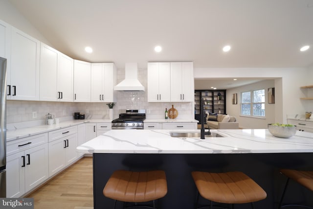 kitchen with light stone counters, white cabinetry, stainless steel range, and custom range hood