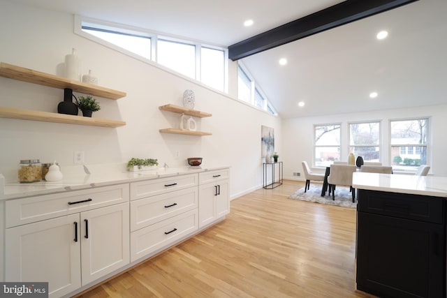 bar with white cabinetry, light hardwood / wood-style flooring, light stone counters, and beamed ceiling