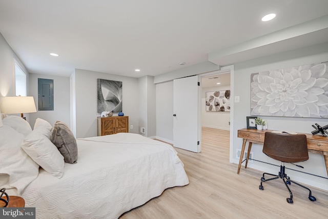 bedroom featuring electric panel, light wood-type flooring, and a closet