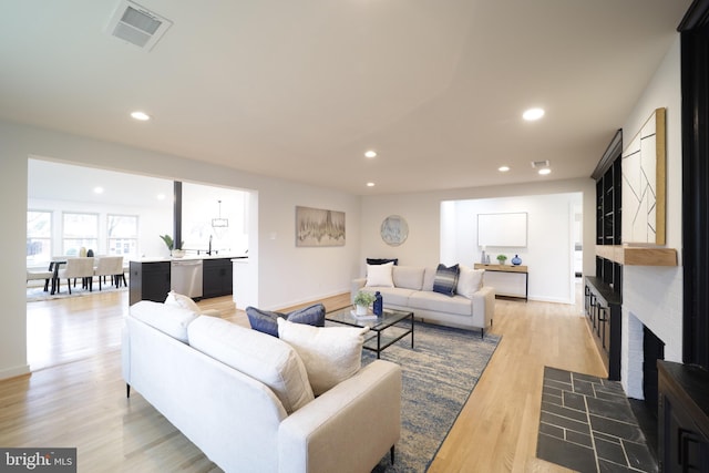 living room featuring sink, a fireplace, and light hardwood / wood-style floors