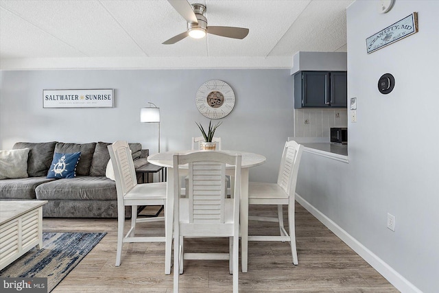 dining area with hardwood / wood-style flooring, a textured ceiling, and ceiling fan