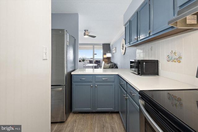 kitchen featuring blue cabinets, tasteful backsplash, light wood-type flooring, stainless steel fridge, and ceiling fan