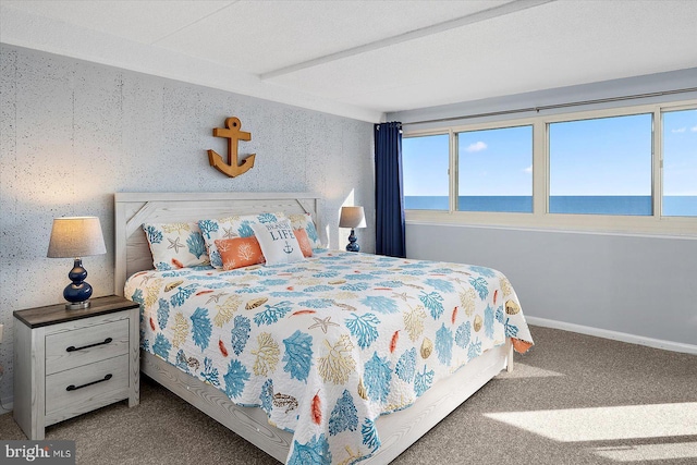 carpeted bedroom featuring beam ceiling and a water view