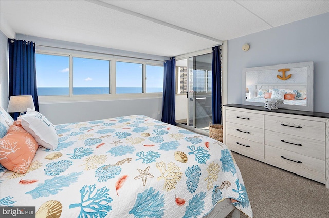 bedroom featuring carpet flooring, a textured ceiling, and a water view