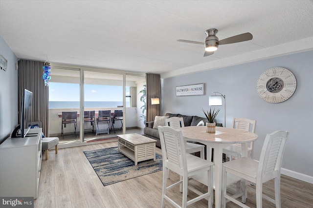 dining room with floor to ceiling windows, ceiling fan, a textured ceiling, and light hardwood / wood-style flooring