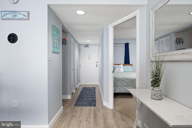 corridor with a textured ceiling and light wood-type flooring