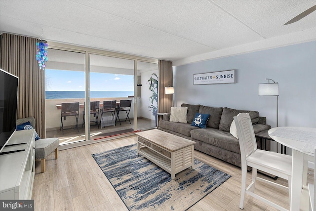 living room featuring a water view, a textured ceiling, and light wood-type flooring