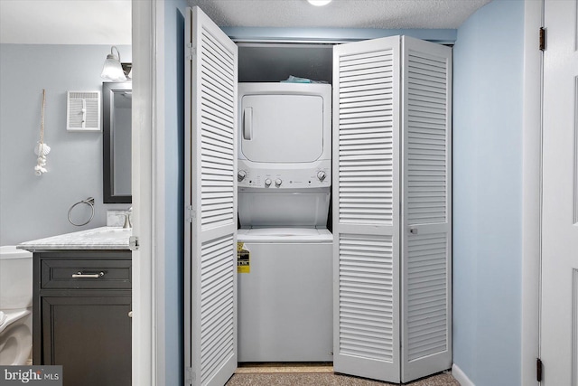 clothes washing area featuring stacked washer and clothes dryer and a textured ceiling