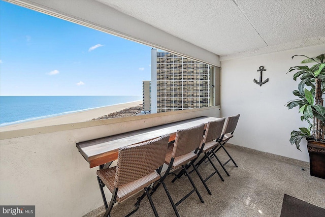 unfurnished dining area with a view of the beach, a wealth of natural light, a textured ceiling, and a water view