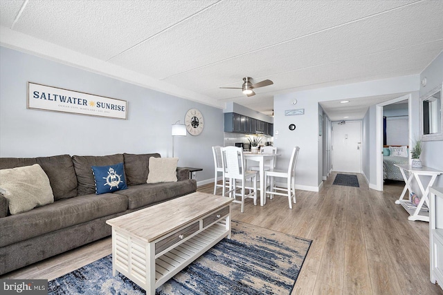 living room featuring a textured ceiling, light hardwood / wood-style floors, and ceiling fan