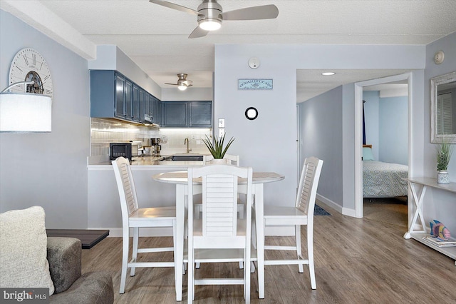 dining room featuring ceiling fan, sink, hardwood / wood-style floors, and a textured ceiling