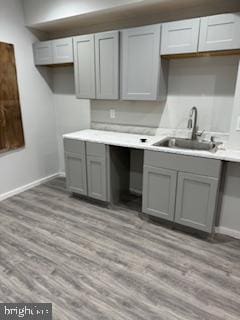 kitchen with sink, gray cabinets, and light wood-type flooring