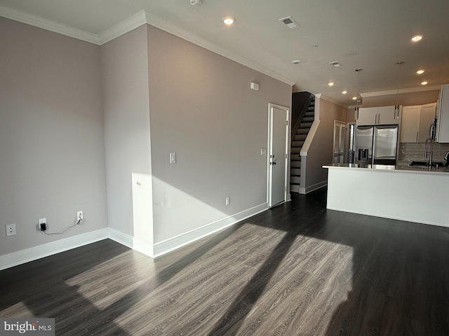 kitchen featuring dark hardwood / wood-style floors, tasteful backsplash, sink, stainless steel fridge, and crown molding