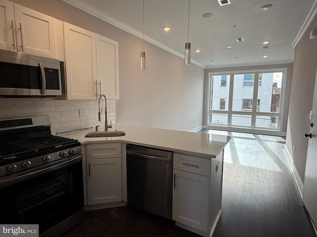 kitchen with sink, appliances with stainless steel finishes, white cabinets, decorative backsplash, and kitchen peninsula