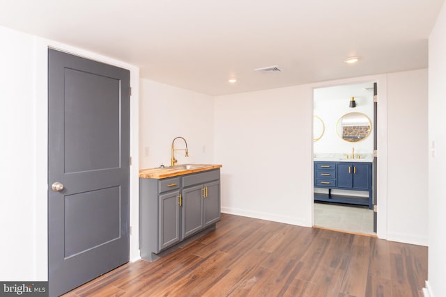 bar featuring wood counters, dark hardwood / wood-style flooring, gray cabinets, and sink