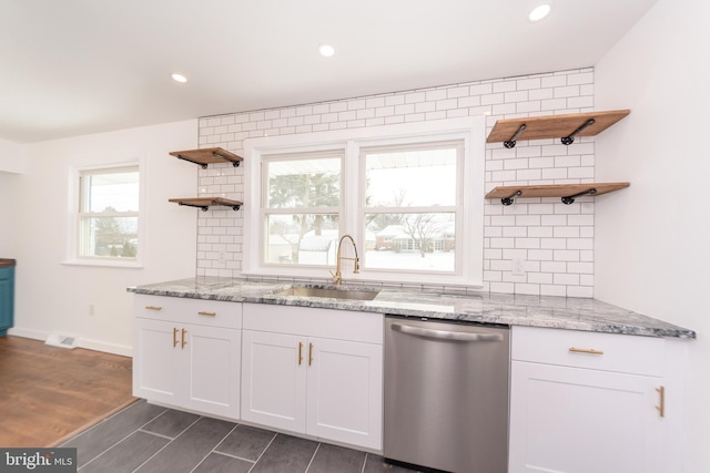 kitchen featuring dishwasher, sink, light stone countertops, and white cabinets