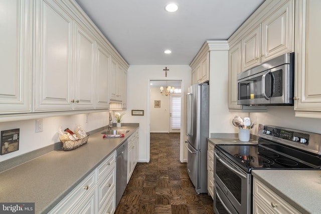 kitchen with dark parquet flooring, sink, a chandelier, hanging light fixtures, and stainless steel appliances