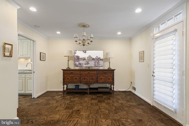 entryway with crown molding, sink, dark parquet flooring, and a chandelier