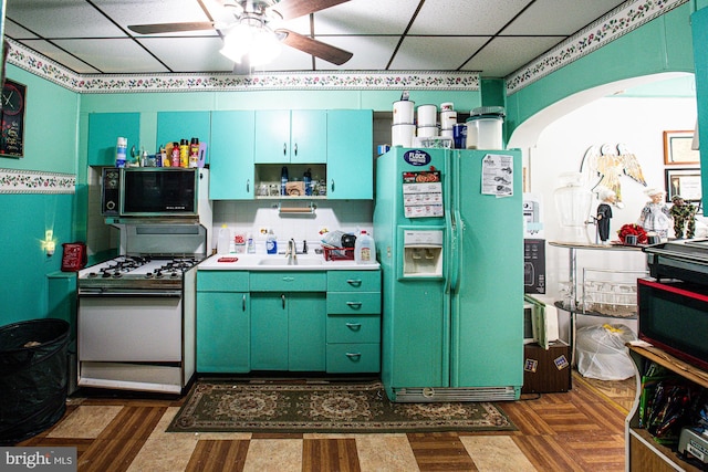 kitchen with white gas range, sink, decorative backsplash, fridge with ice dispenser, and a drop ceiling