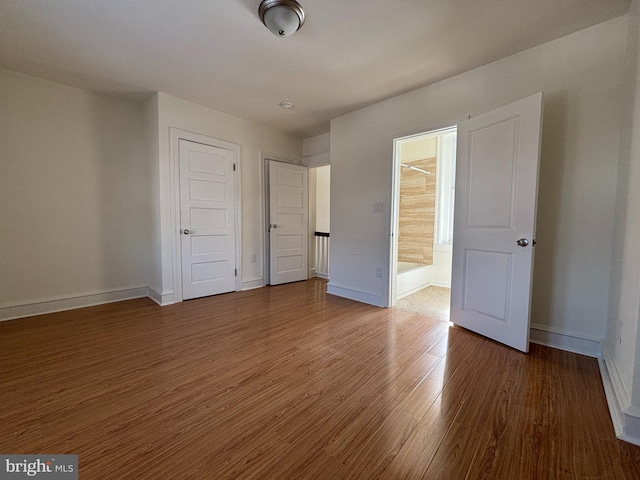 unfurnished bedroom featuring dark wood-type flooring, connected bathroom, and a closet