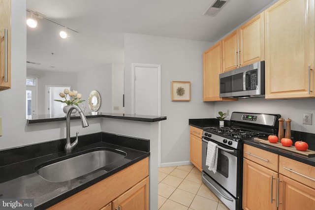 kitchen featuring light tile patterned floors, stainless steel appliances, visible vents, light brown cabinets, and a sink