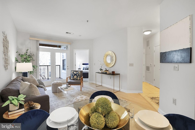 living area with light wood finished floors, visible vents, and baseboards