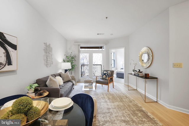 living area with baseboards, visible vents, and wood finished floors