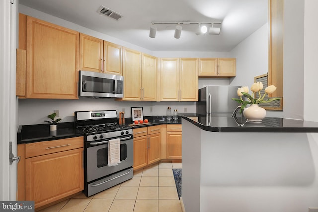 kitchen featuring light tile patterned floors, stainless steel appliances, dark countertops, visible vents, and a peninsula