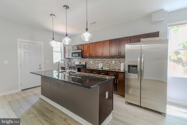 3603 Oakmont Ave, Baltimore, MD 21215 - kitchen with appliances with stainless steel finishes, tasteful backsplash, light wood-type flooring, a kitchen island with sink, and a sink