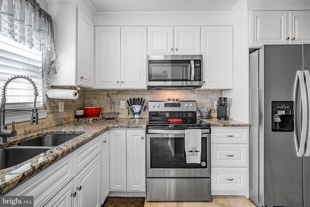 kitchen featuring sink, white cabinetry, appliances with stainless steel finishes, stone counters, and backsplash