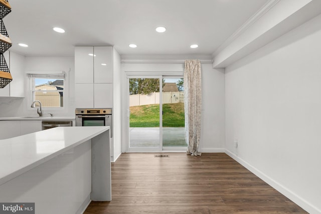 kitchen featuring appliances with stainless steel finishes, dark hardwood / wood-style floors, white cabinetry, sink, and ornamental molding