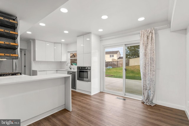 kitchen featuring sink, white cabinetry, dark hardwood / wood-style flooring, stainless steel appliances, and decorative backsplash