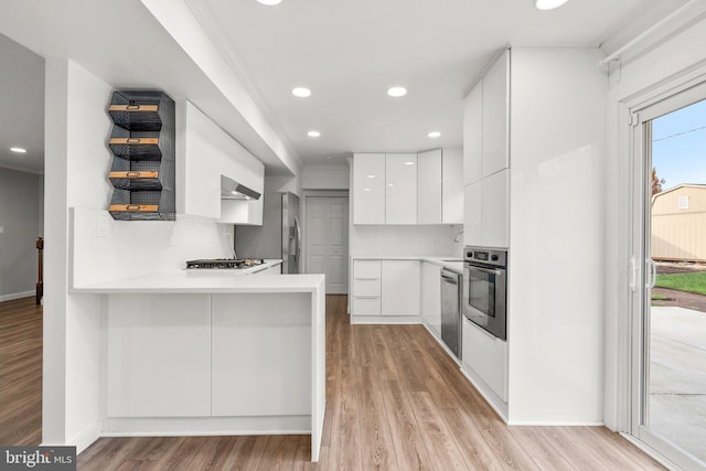 kitchen featuring white cabinetry, stainless steel appliances, kitchen peninsula, and backsplash