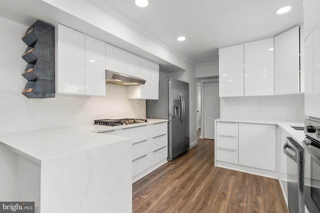 kitchen featuring stainless steel appliances, dark hardwood / wood-style floors, white cabinets, and backsplash