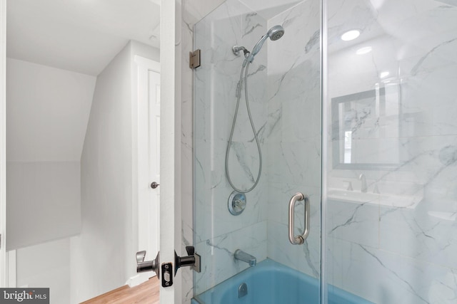 bathroom with hardwood / wood-style flooring and combined bath / shower with glass door