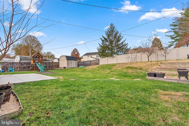 view of yard featuring a storage unit, a playground, and a patio