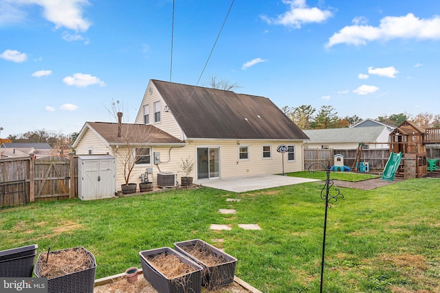 back of house featuring a playground, a lawn, cooling unit, a patio area, and a storage shed