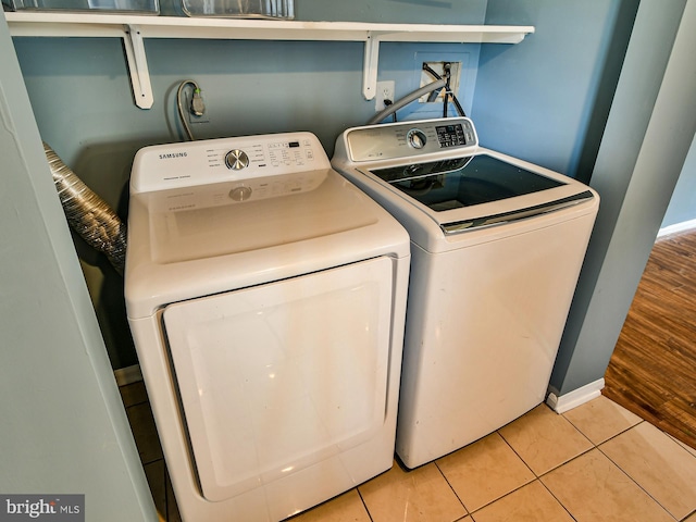 laundry area with washing machine and dryer and light tile patterned floors