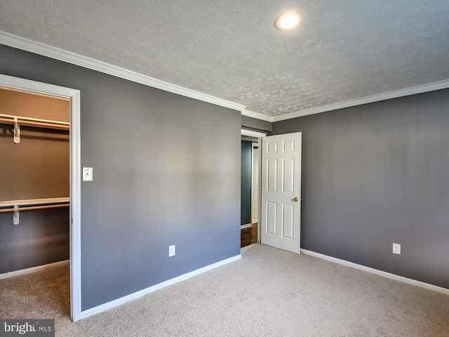 unfurnished bedroom featuring carpet floors, a spacious closet, crown molding, a textured ceiling, and a closet