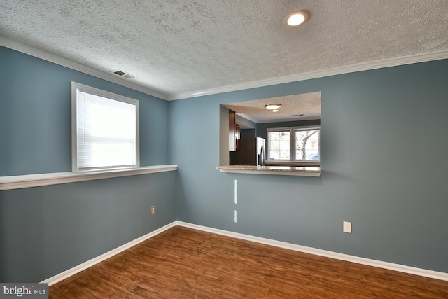 unfurnished room with crown molding, wood-type flooring, and a textured ceiling