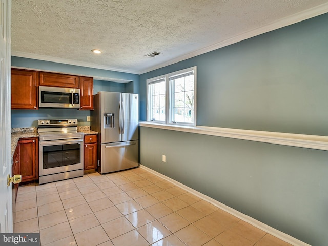 kitchen featuring light tile patterned floors, ornamental molding, stainless steel appliances, and a textured ceiling