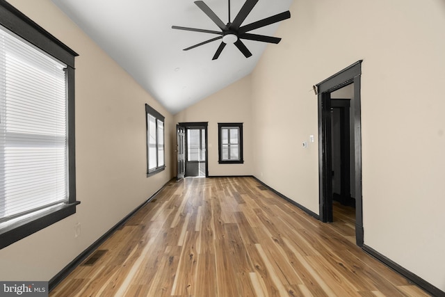 empty room with high vaulted ceiling, ceiling fan, and light wood-type flooring