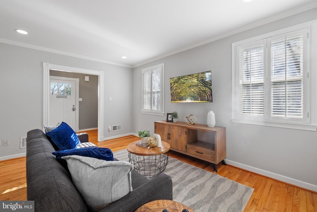 living room with hardwood / wood-style flooring, ornamental molding, and a healthy amount of sunlight