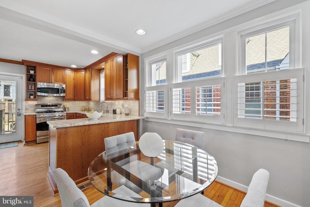 dining area featuring sink, light hardwood / wood-style flooring, and ornamental molding