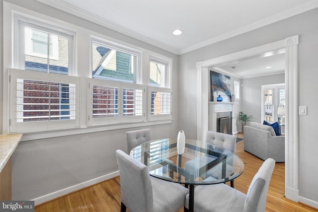 dining room with a wealth of natural light, ornamental molding, and light hardwood / wood-style floors