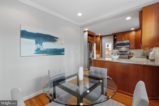 dining room with sink, crown molding, and wood-type flooring