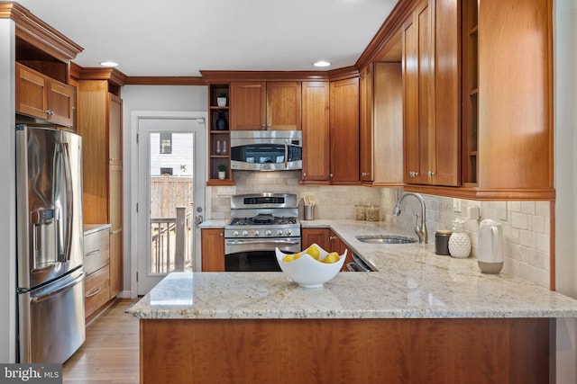 kitchen with stainless steel appliances, light stone counters, and kitchen peninsula