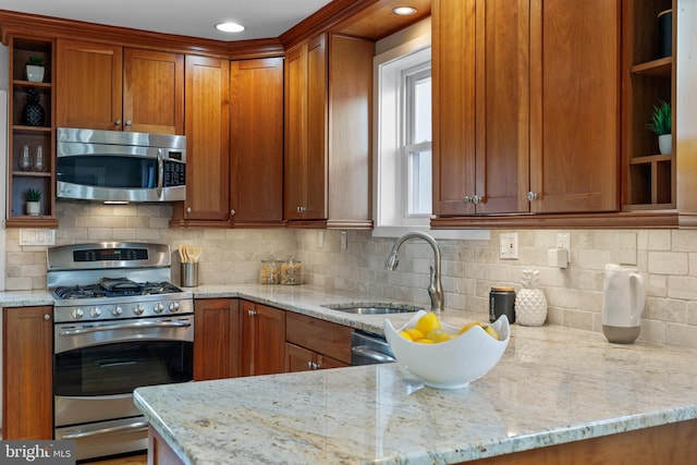 kitchen with stainless steel appliances, sink, light stone counters, and decorative backsplash